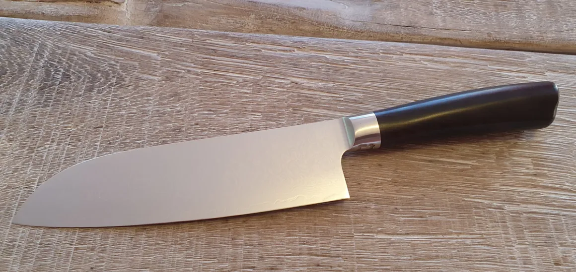 Udpakket Santoku kniv liggende på et plankebord